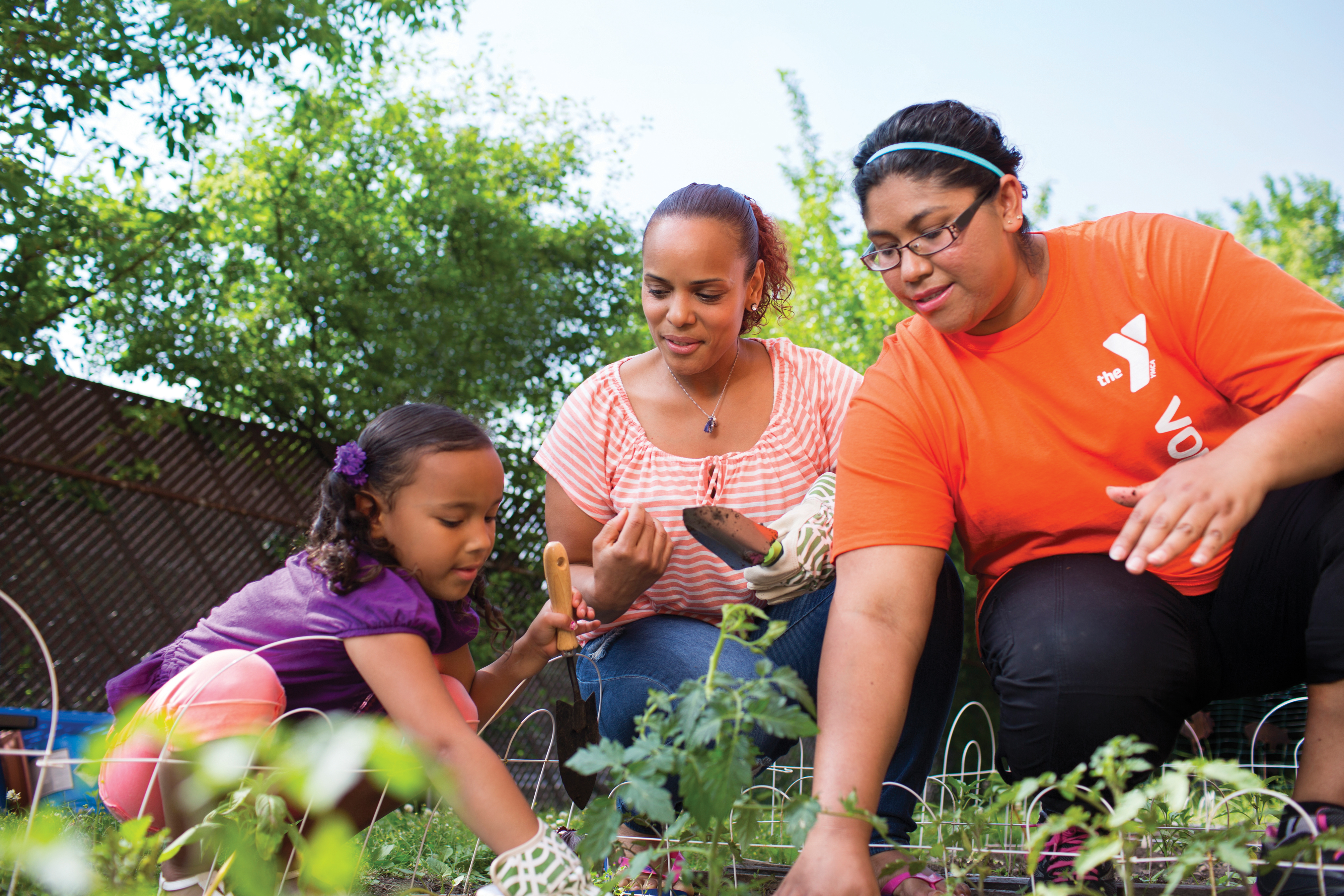 YMCA staff member showing youth girl how to garden