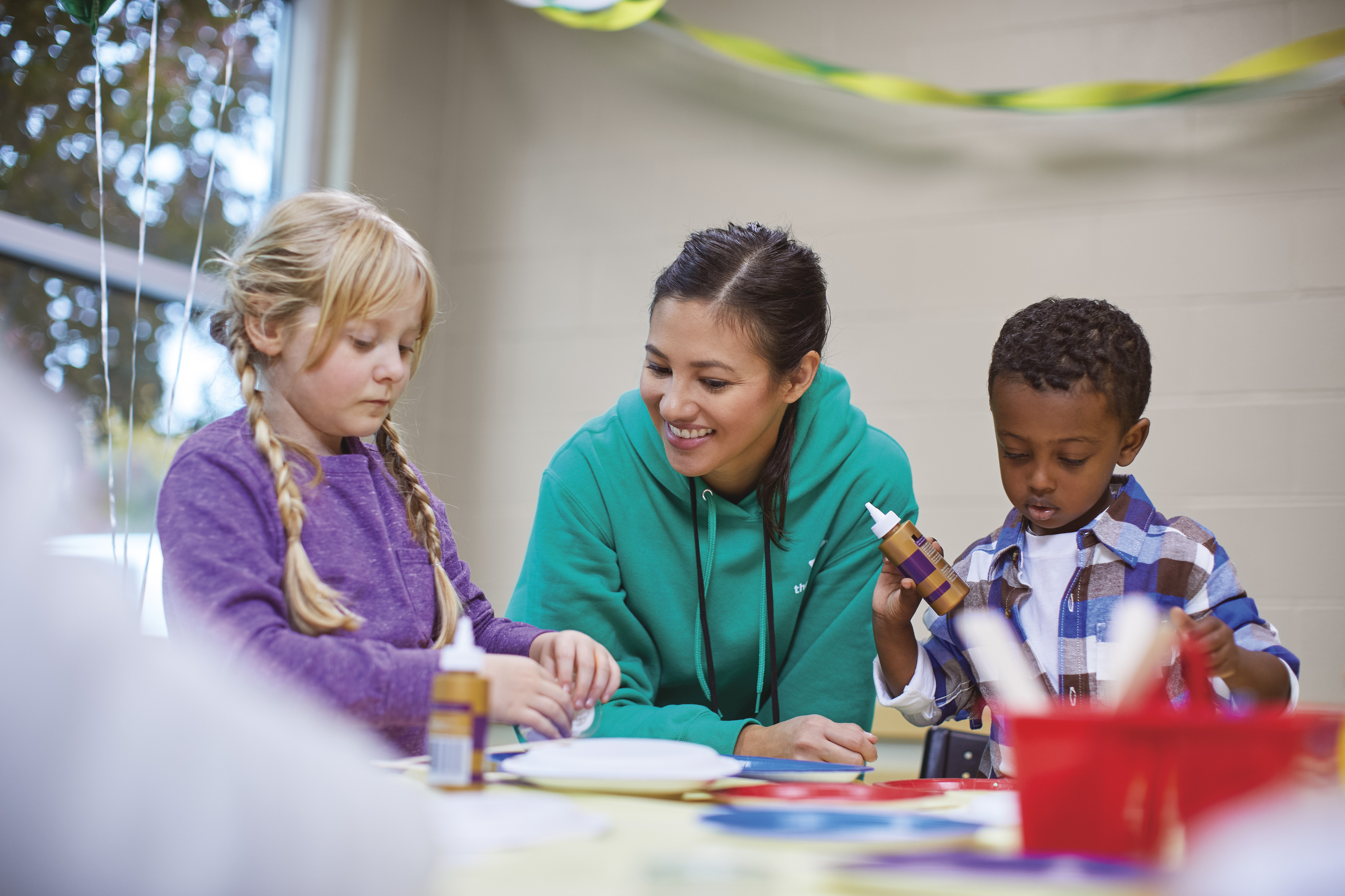 YMCA faculty helping kids craft during a birthday party YMCA faculty helping kids craft during a birthday party