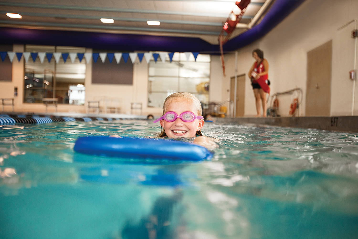 Young girl in pool with kick board  Young girl in pool with kick board