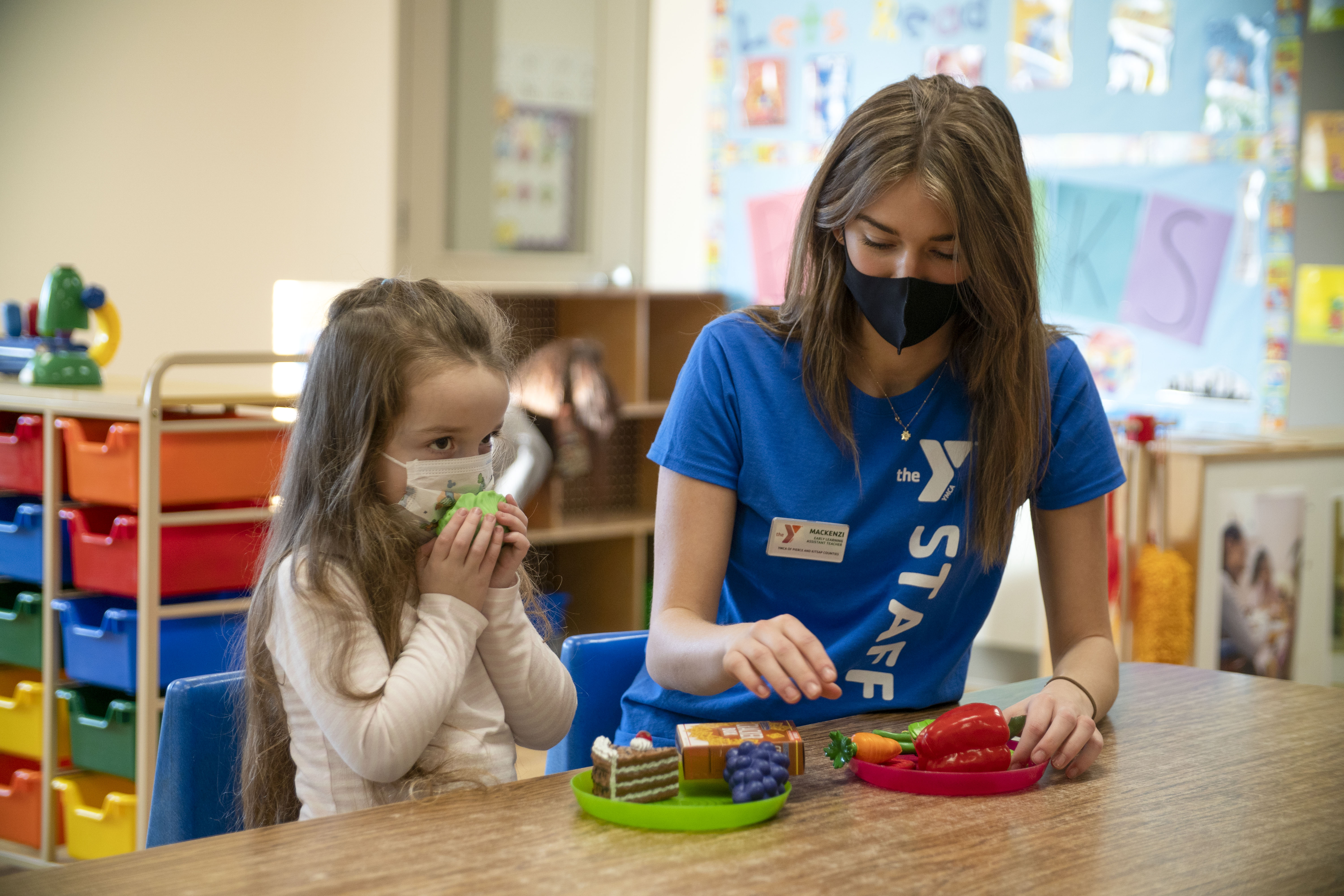 Child sitting in playroom with staff member 