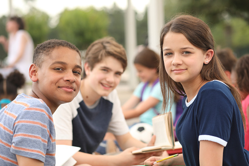 children sitting outdoors doing homework