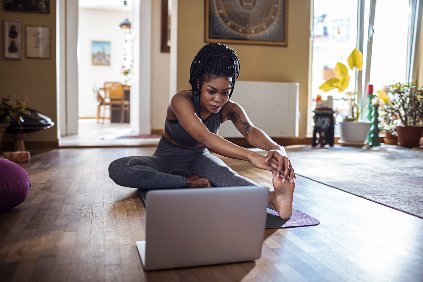 woman sitting at home on yoga mat participating in YMCA class online