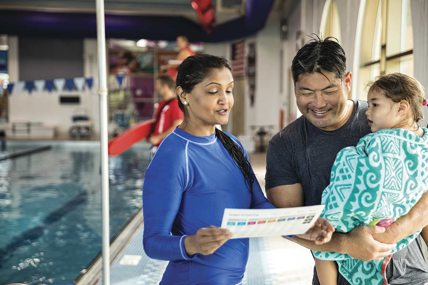 Parent at pool with toddler talking with instructor