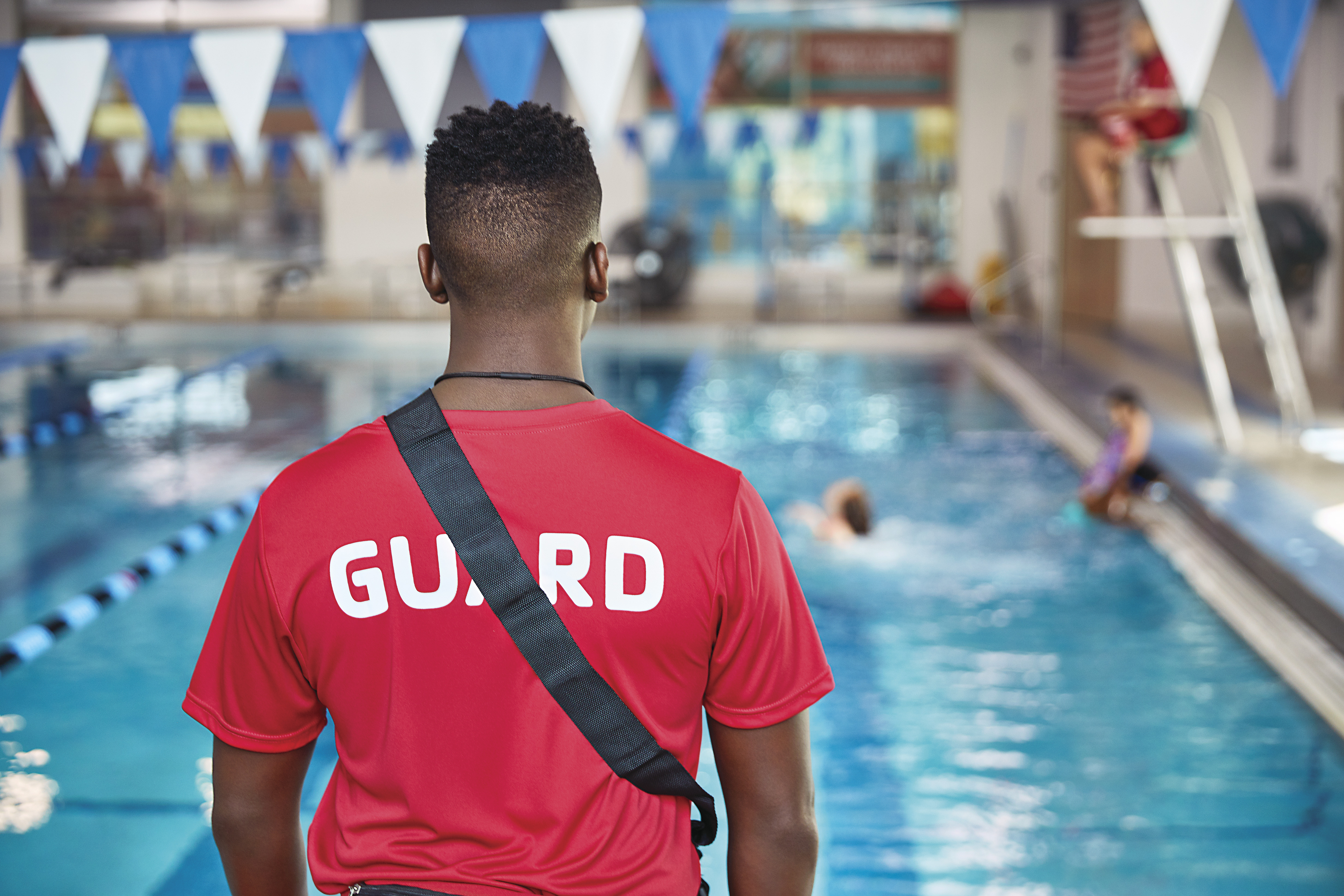 Lifeguard overlooking pool while children play Lifeguard overlooking pool while children play
