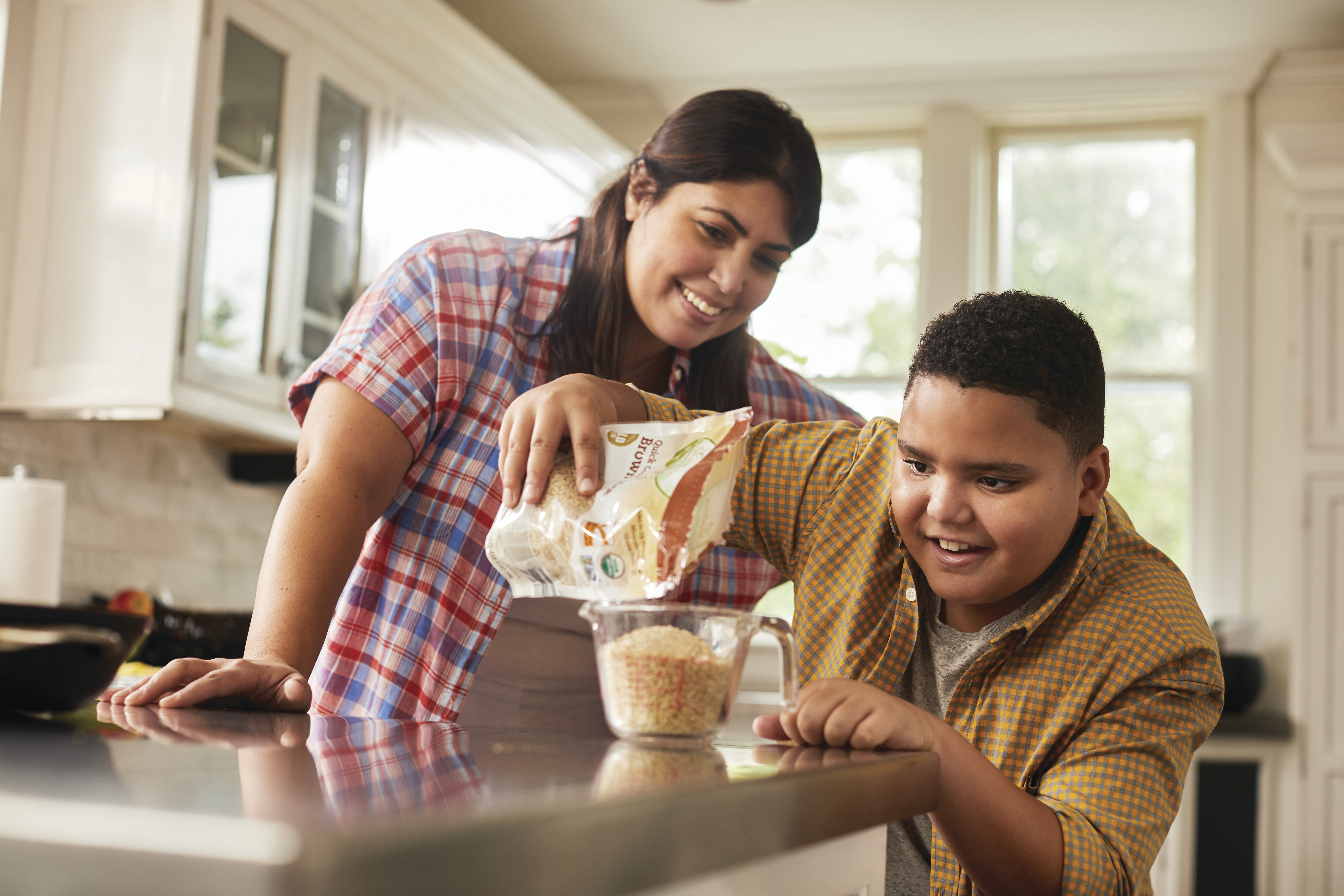 Parent and teen pouring grains in measuring cup Parent and teen pouring grains in measuring cup