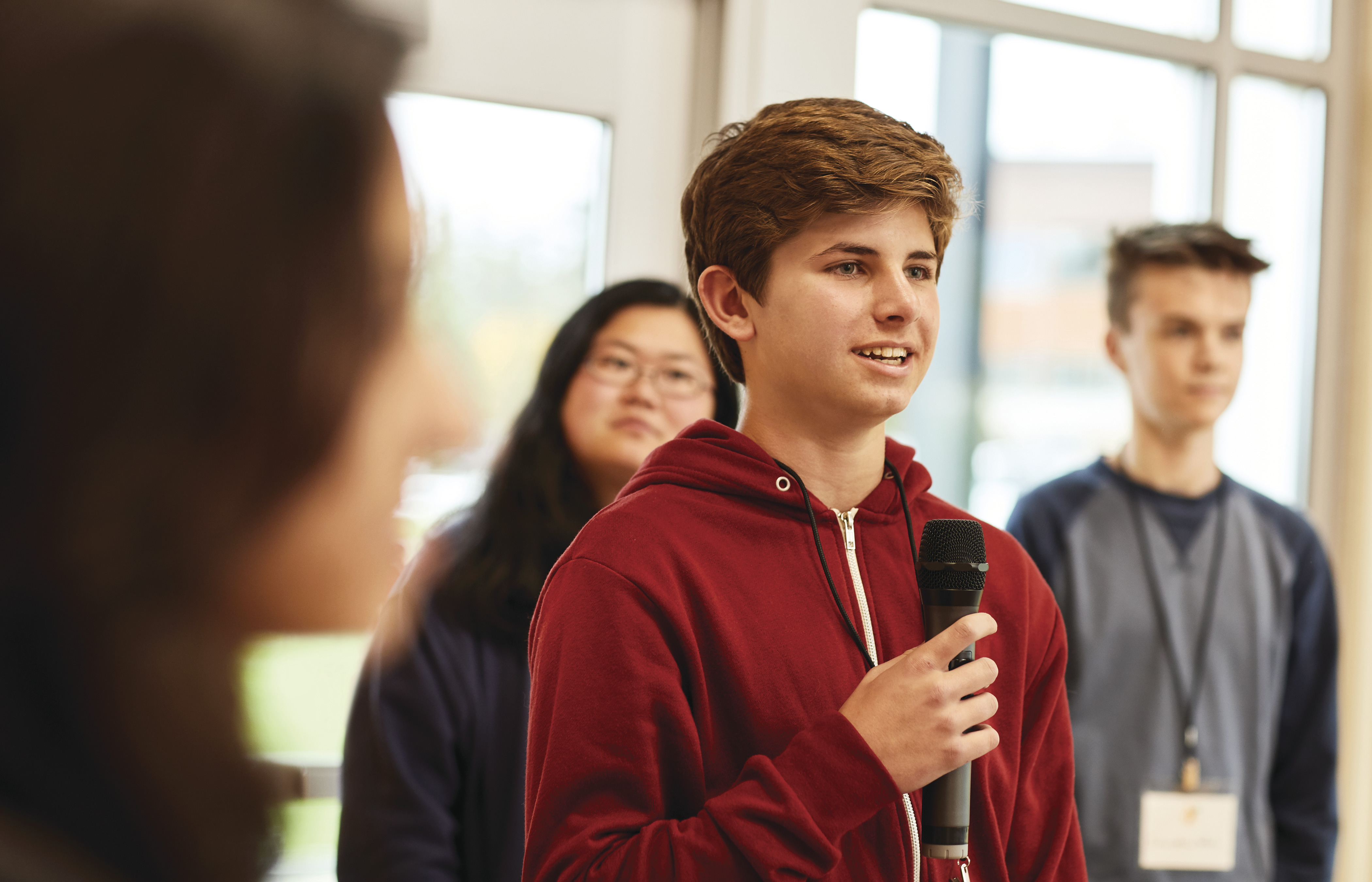 Teen speaking to a group with microphone in hand
