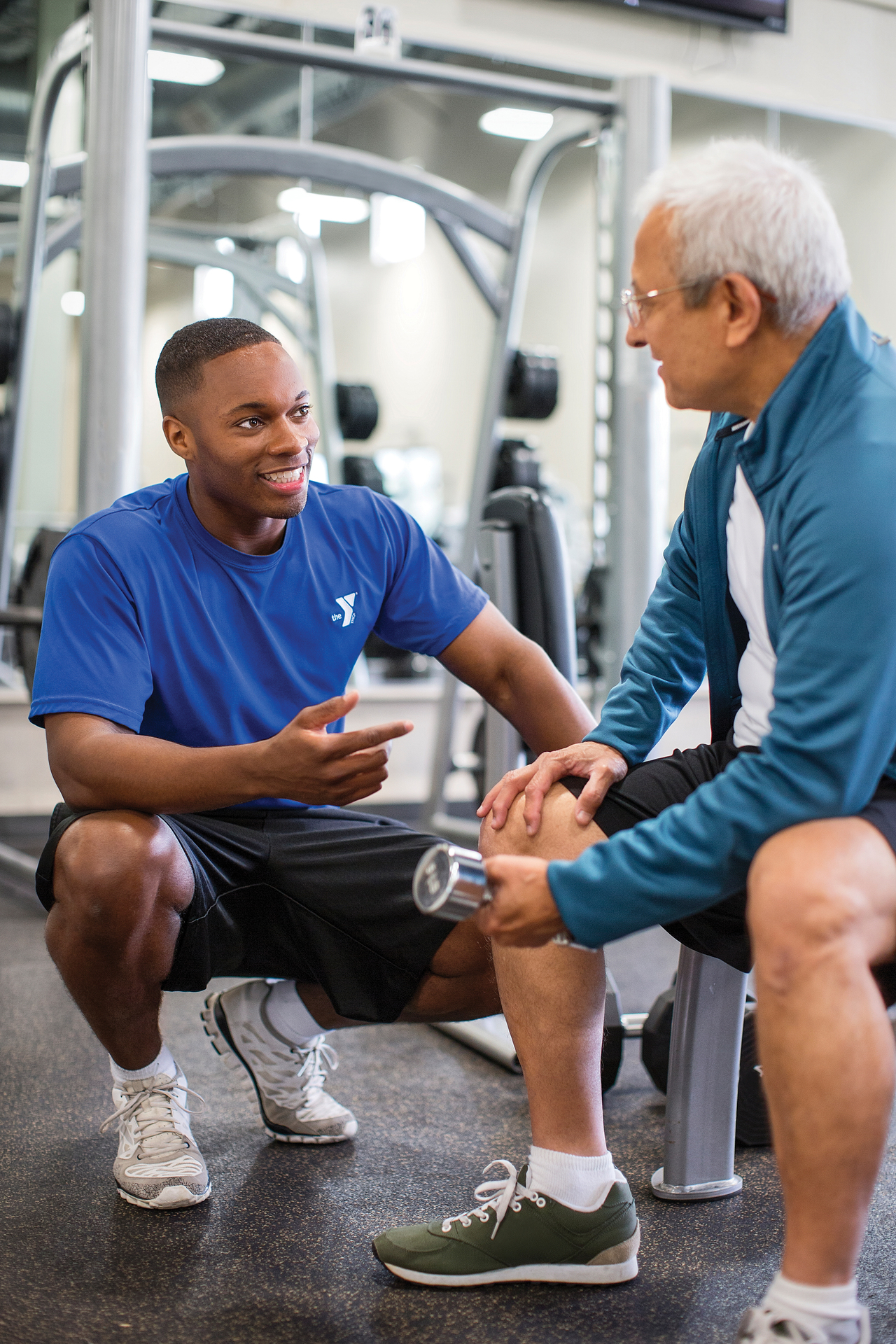 YMCA trainer assisting member with weights