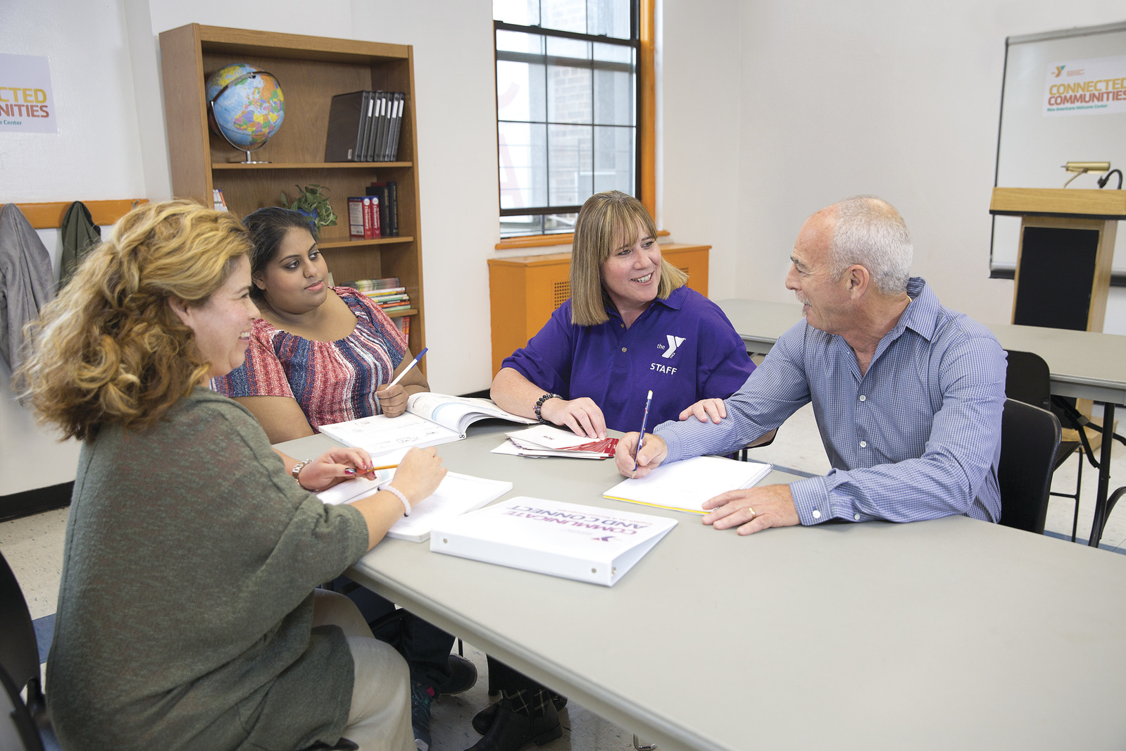 Y Staff providing newcomer resources to 3 adults in a classroom setting Y Staff providing newcomer resources to 3 adults in a classroom setting