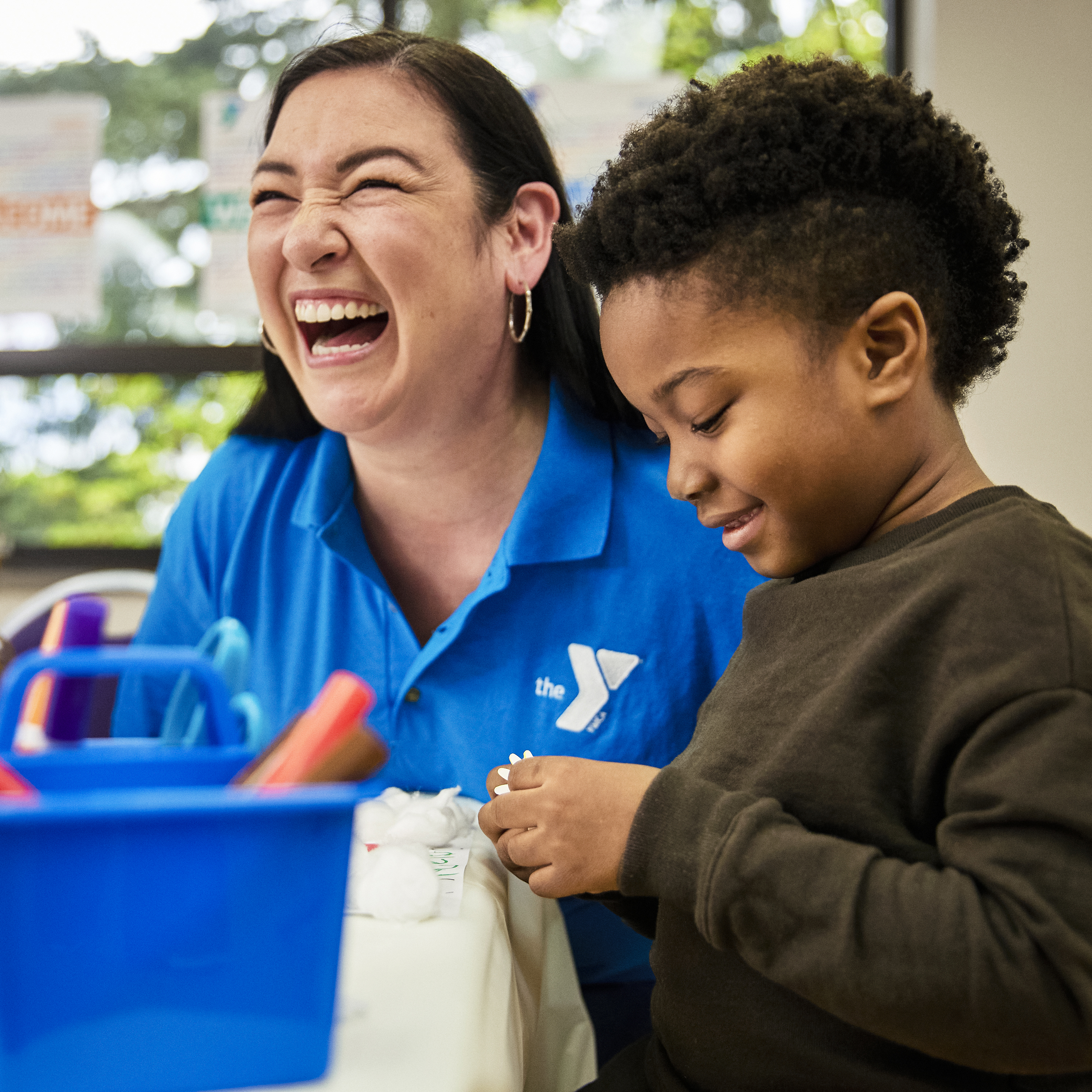 Female staff person in blue Y shirt laughing with young boy. Female staff person in blue Y shirt laughing with young boy.