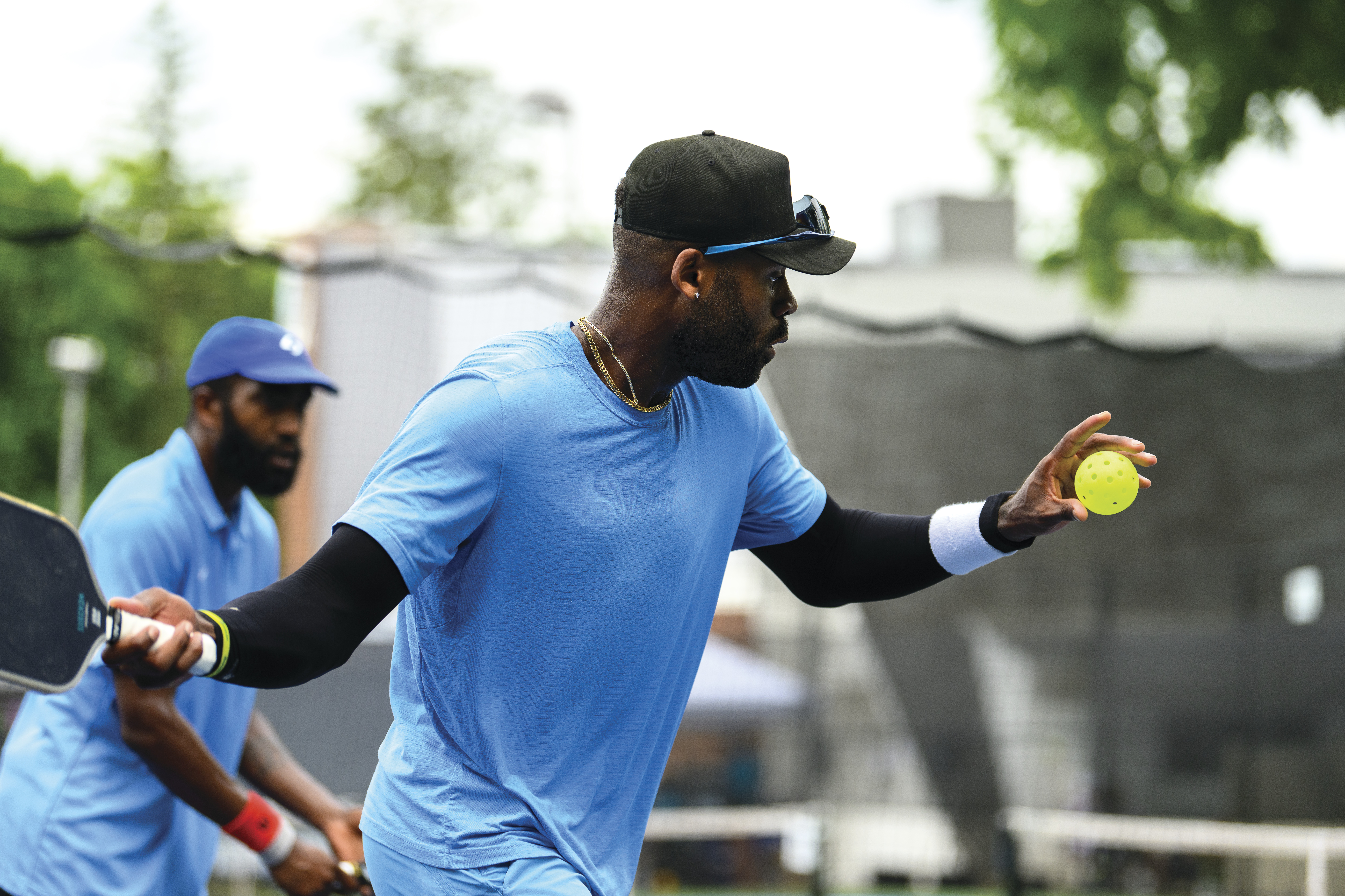 Two men in blue shirts playing pickleball