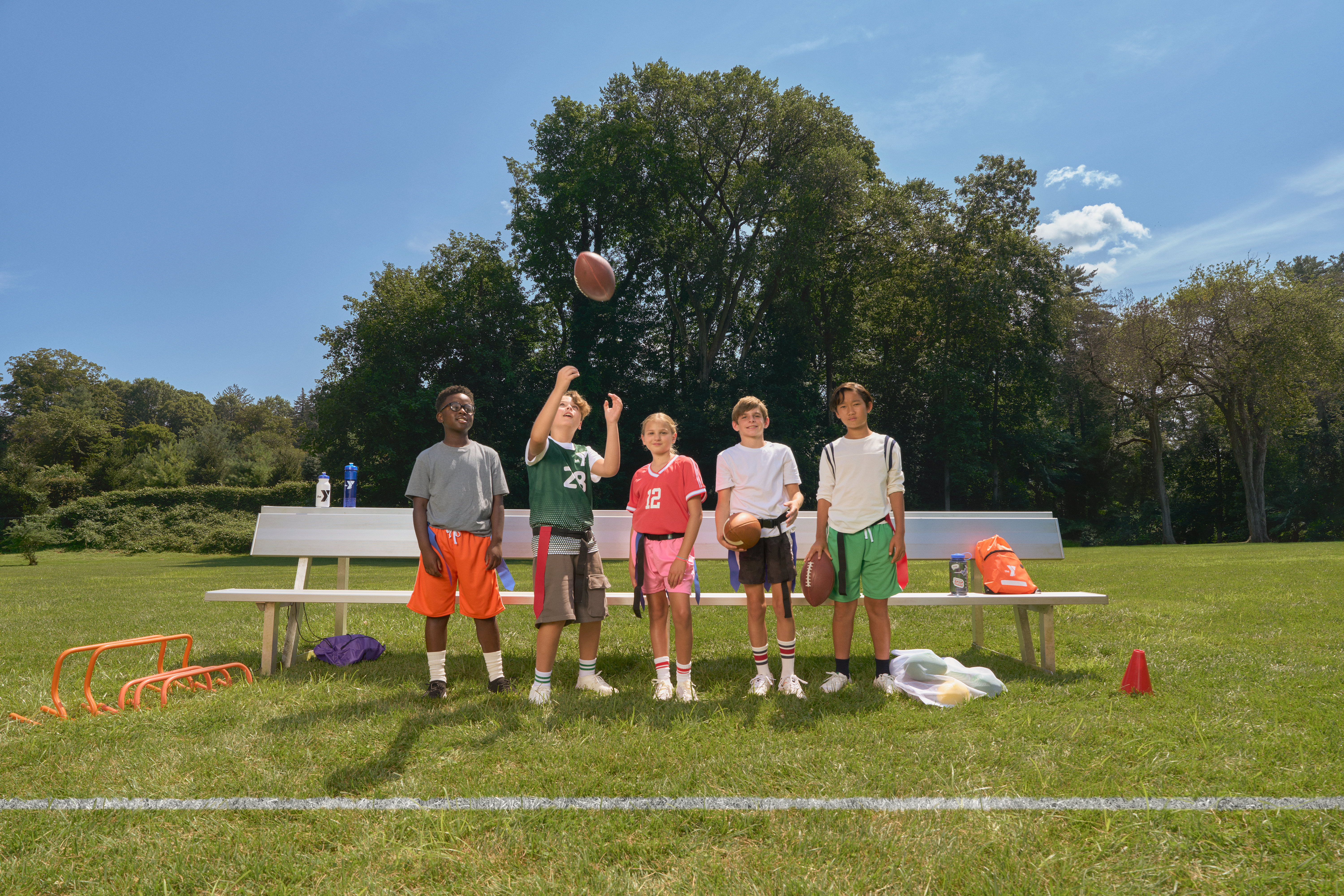 YMCA youth pose while playing flag football on a field outdoors