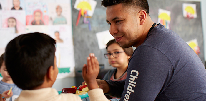 Adult smiling at child in a classroom