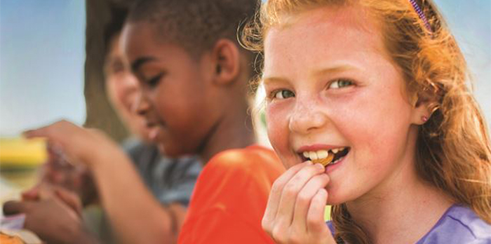 Closeup of smiling kids eating outside