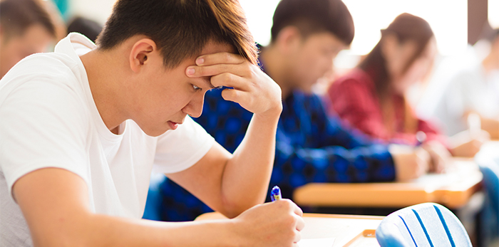 Teen focusing on taking a test in a classroom