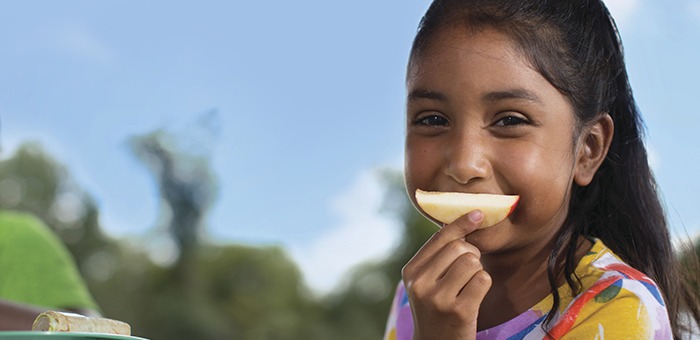 Smiling child eating an apple slice