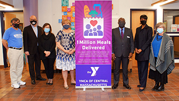 Seven people standing by a sign that says "1 million meals delivered, YMCA of Central Massachusetts"