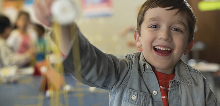 Smiling child in a classroom building a toy