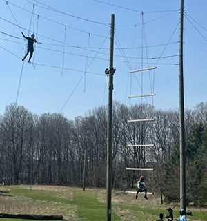 Wide shot of people on a ropes course against a blue sky