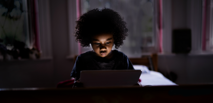 Child sitting in the dark staring at a screen