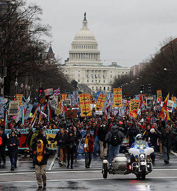 Large group of people marching on the street with the U.S. Capitol looming in the background