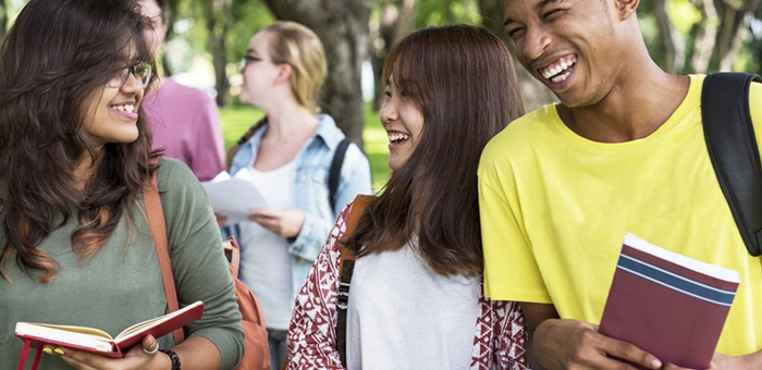 Teens smiling and laughing carrying books