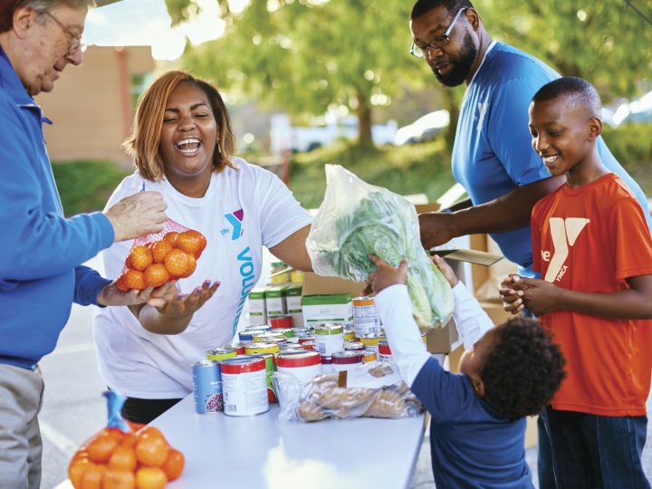 A Y volunteer smiles while distributing groceries