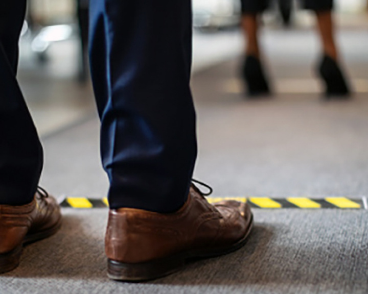 Man's feet standing behind yellow-black hazard tape