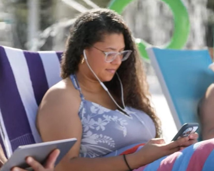 woman on her phone while sitting by a pool