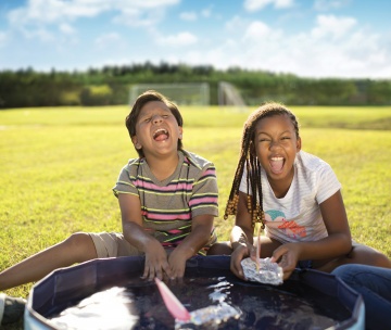 Two kids making floating homemade boats in a small inflatable pool