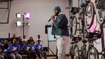 LeBron James speaking on stage in front of bicycles