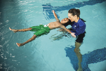 Instructor teaching child to swim - YMCA