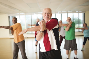 Seniors in group fitness class stretching their arms