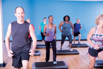 Studio group fitness class doing step aerobics at YMCA