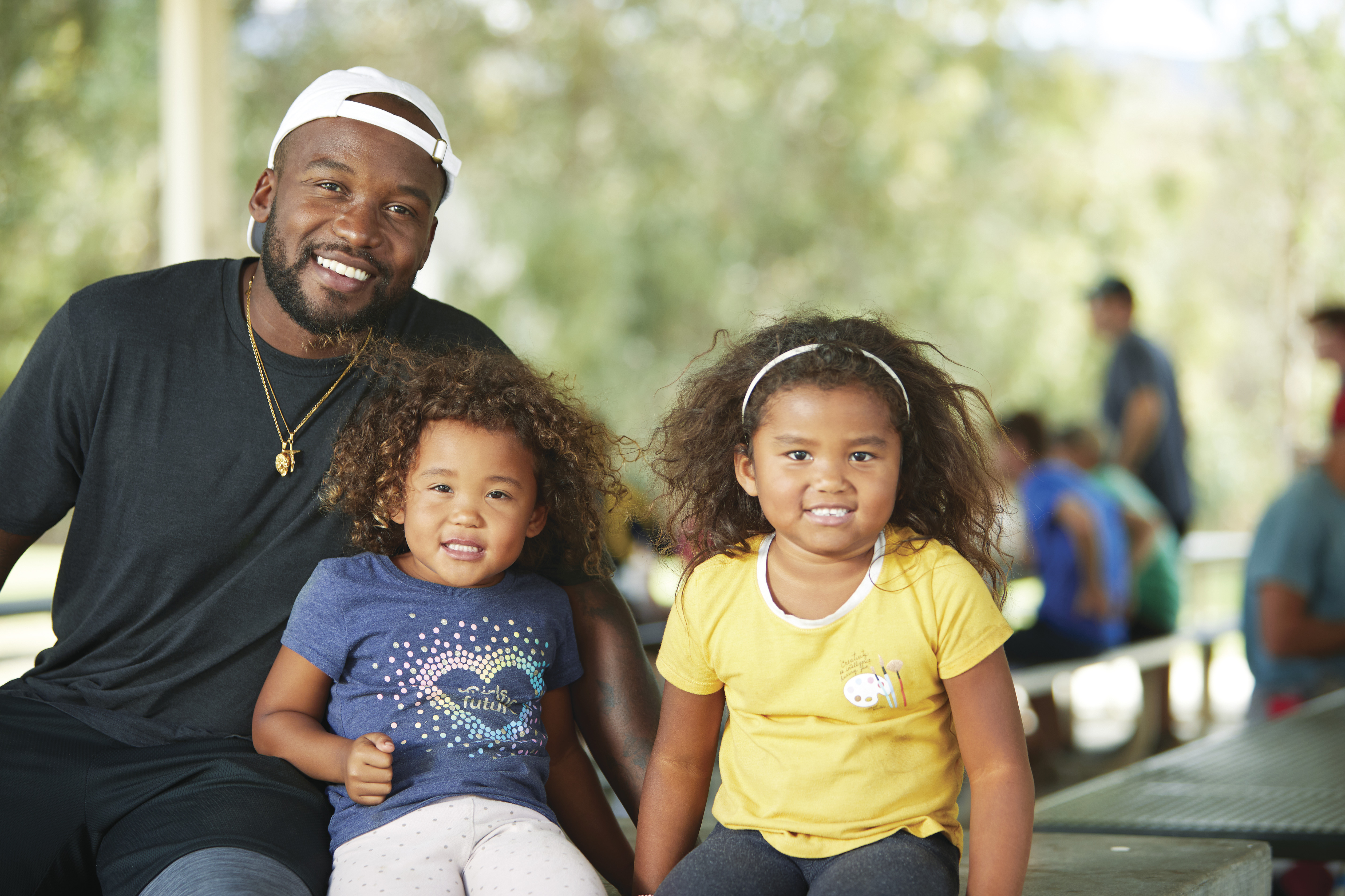 Father posing with two daughters at park - YMCA Father posing with two daughters at park - YMCA