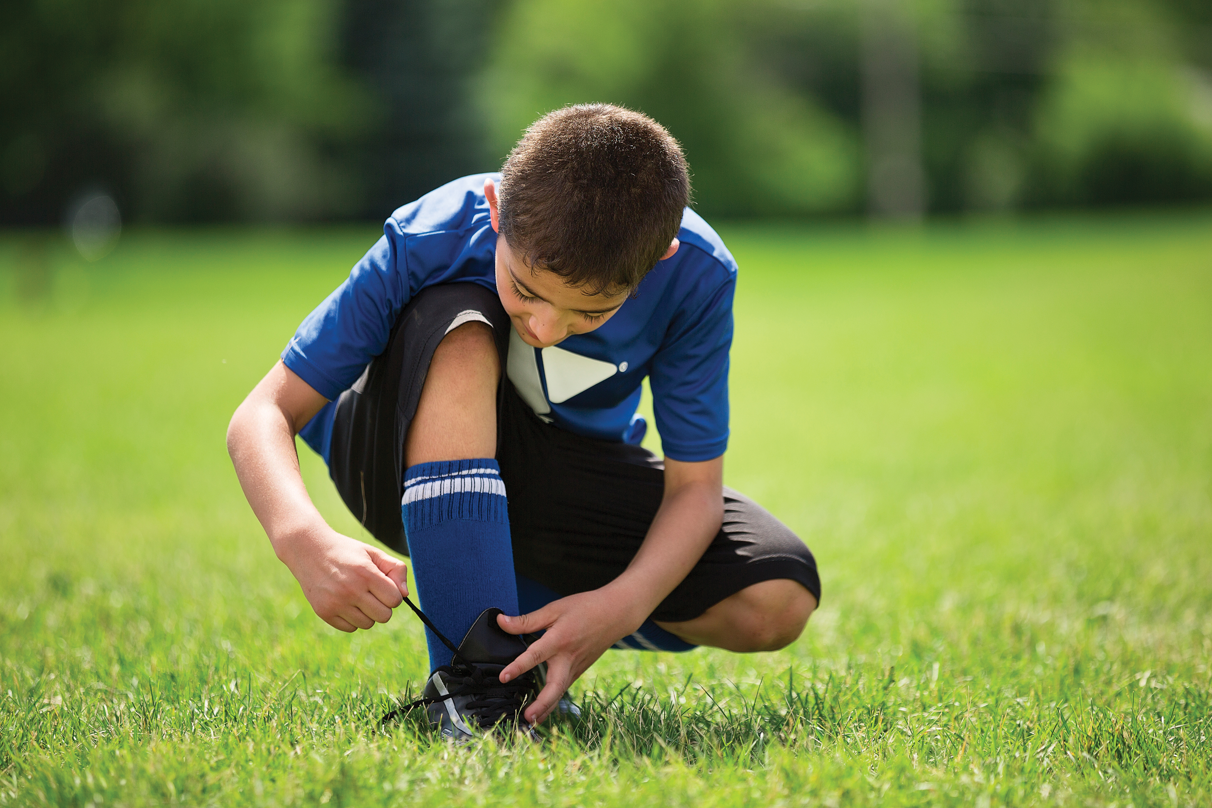 Youth in field tying shoe Youth in field tying shoe