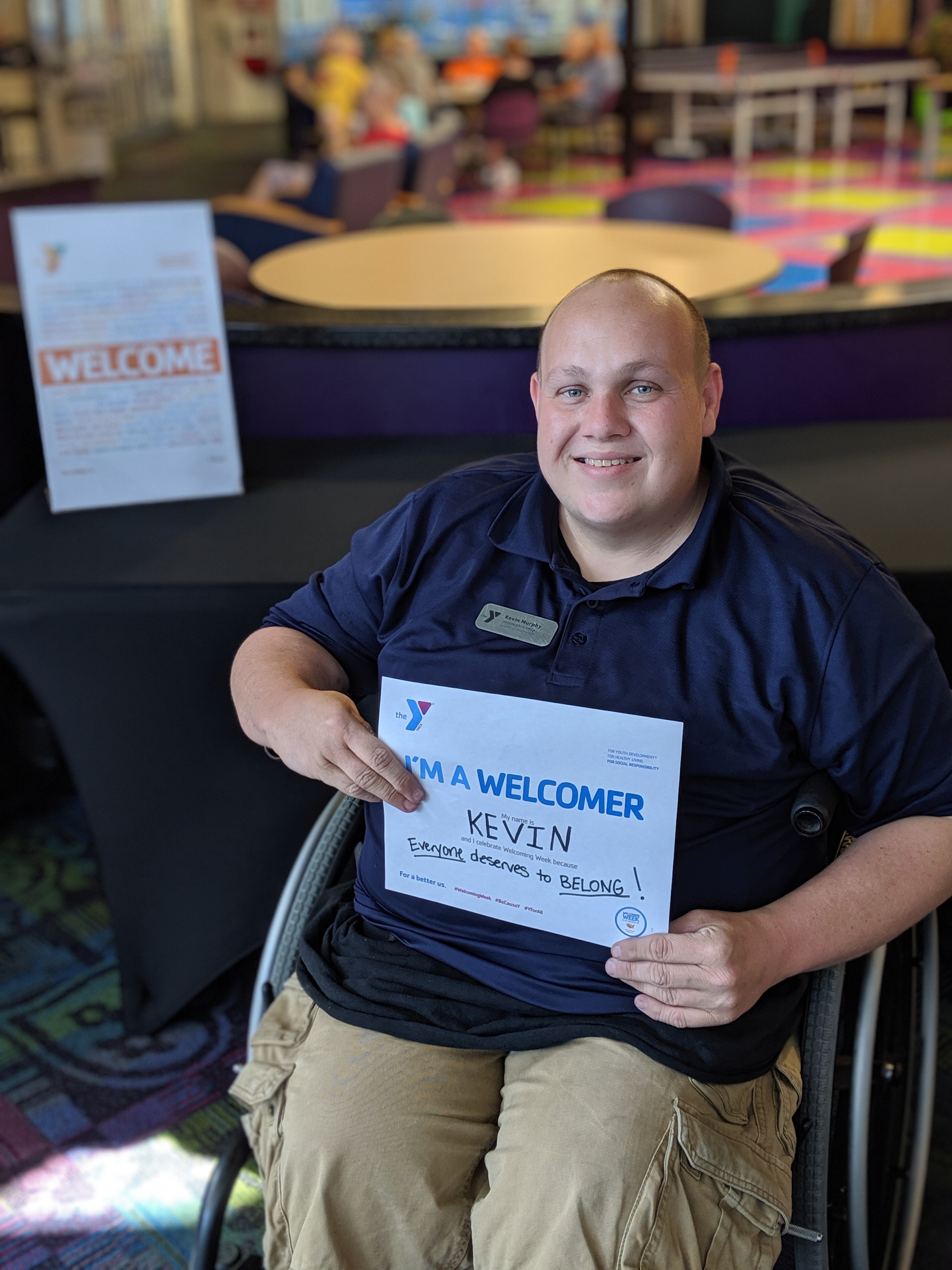 man sitting in wheelchair holding a welcome to the Y sign man sitting in wheelchair holding a welcome to the Y sign