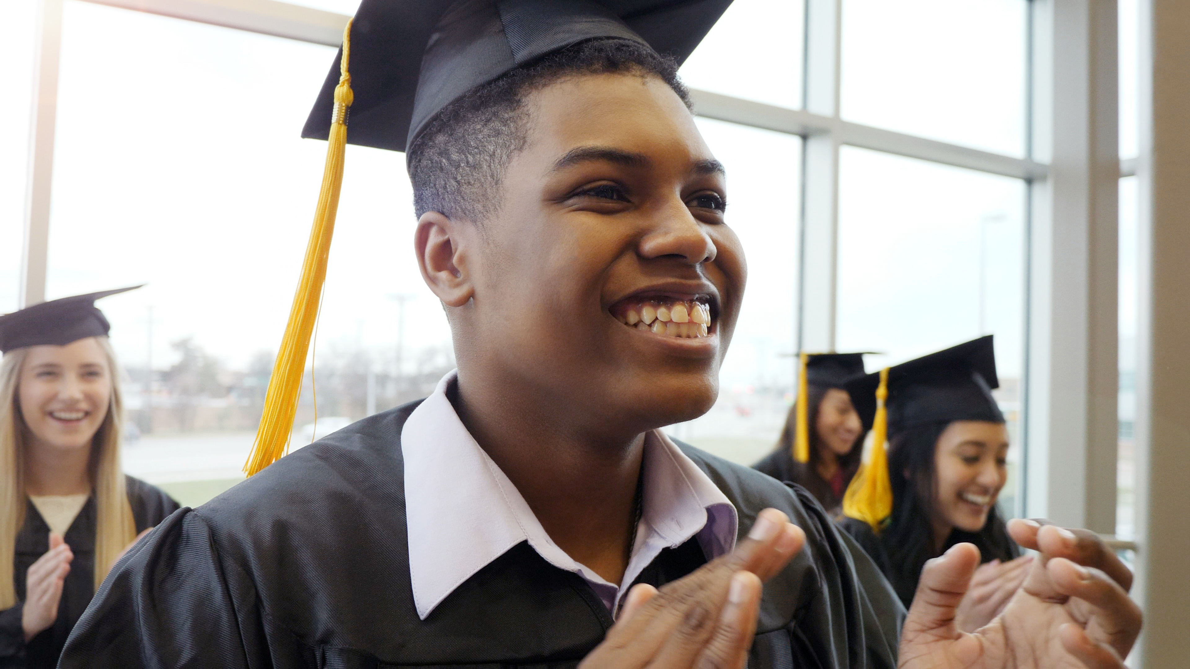 African American male smiling wearing graduation cap and gown African American male smiling wearing graduation cap and gown