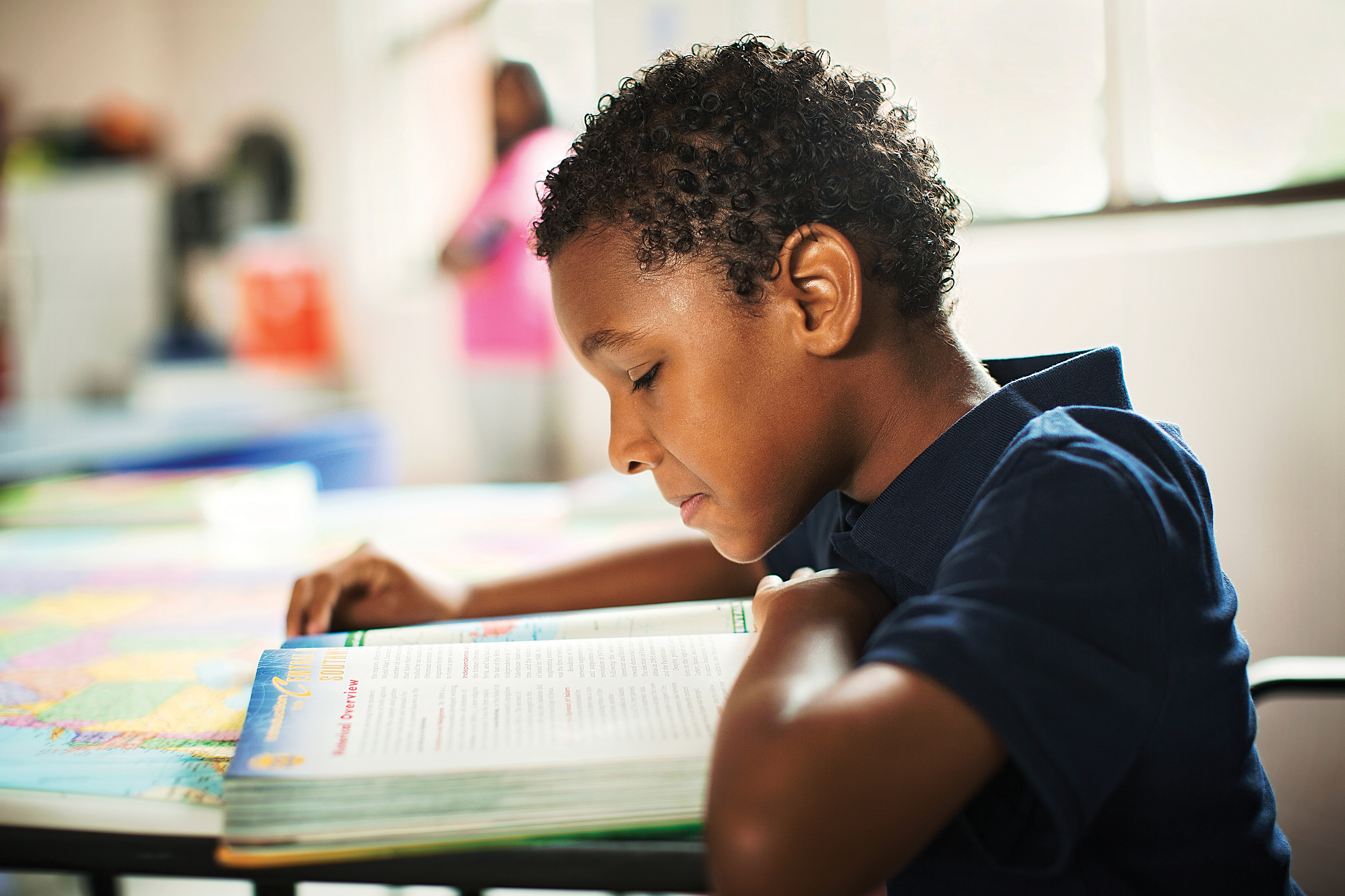 Pre-teen boy reading a textbook in a classroom. Pre-teen boy reading a textbook in a classroom.
