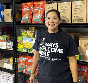 Bedimar Munoz in front of the New American Welcome Center's food pantry