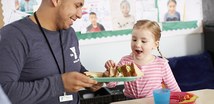 Man serves excited child a healthy meal