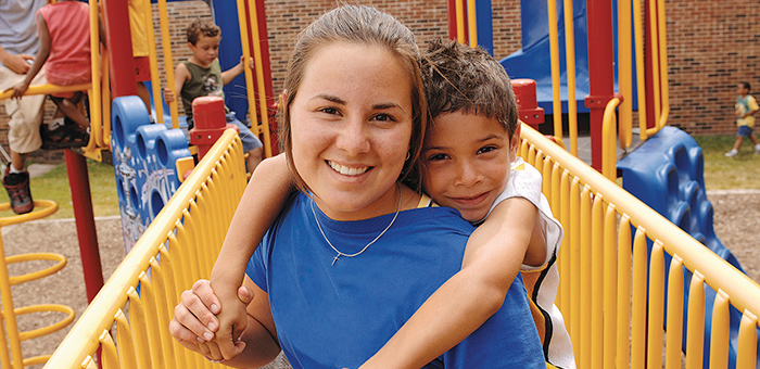 Teen and child smiling while playing on jungle gym