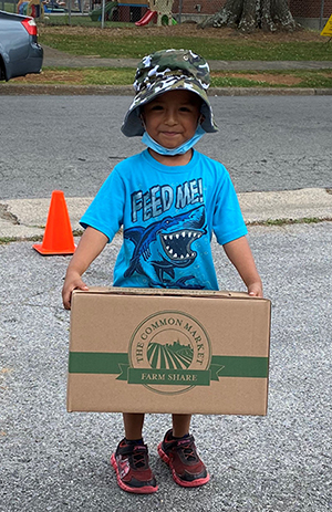 Boy holding a box of produce from YMCA of Rome & Floyd County