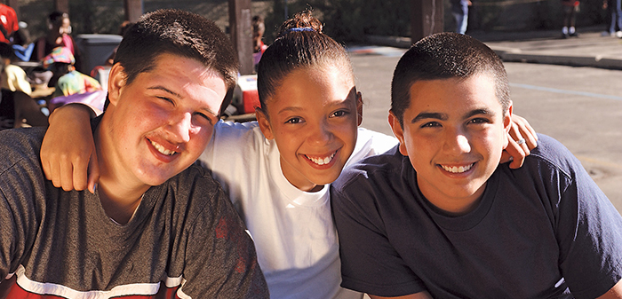 Three teens smiling with arms around each other