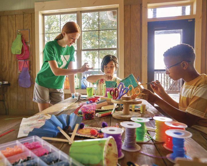 Camp counselor and two campers making crafts inside a cabin Camp counselor and two campers making crafts inside a cabin