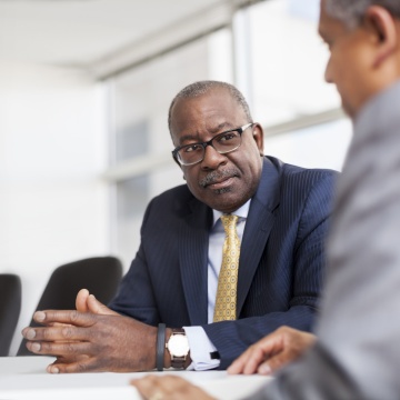 Kevin Washington sitting in boardroom speaking to a man Kevin Washington sitting in boardroom speaking to a man